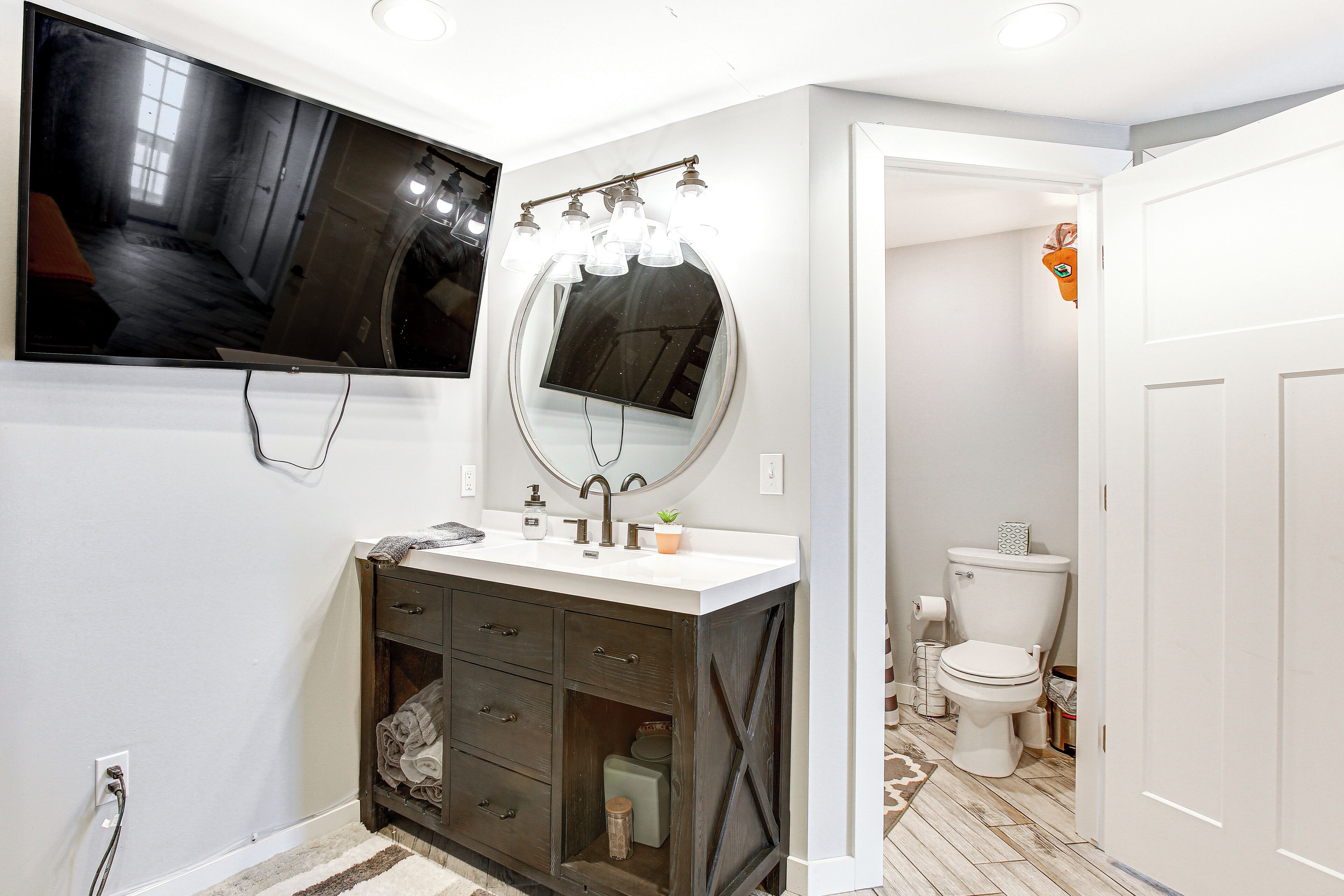 A bathroom with a vanity, mirror, sink, and toilet.