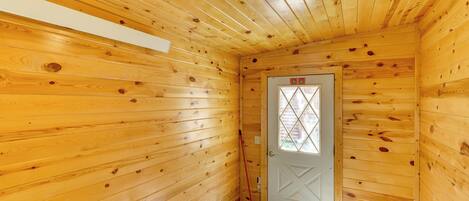A wooden interior with a door, a light fixture, and a white wall.