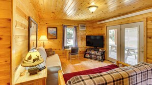 Een gezellig chalet met een bed, een bureau met lamp, een televisie en een boekenkast.