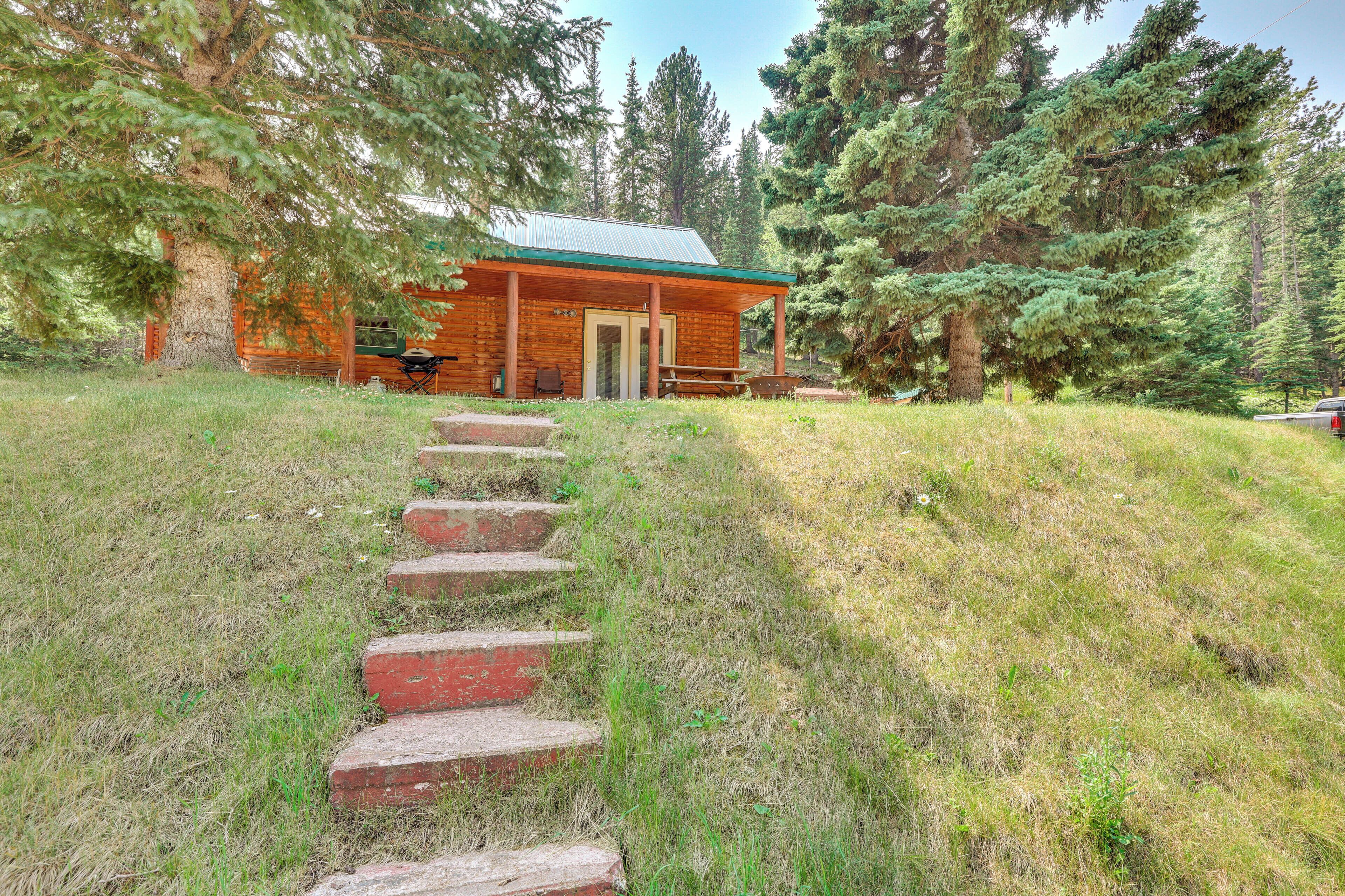 A cabin with a porch, a picnic table, and a staircase leading to the entrance.