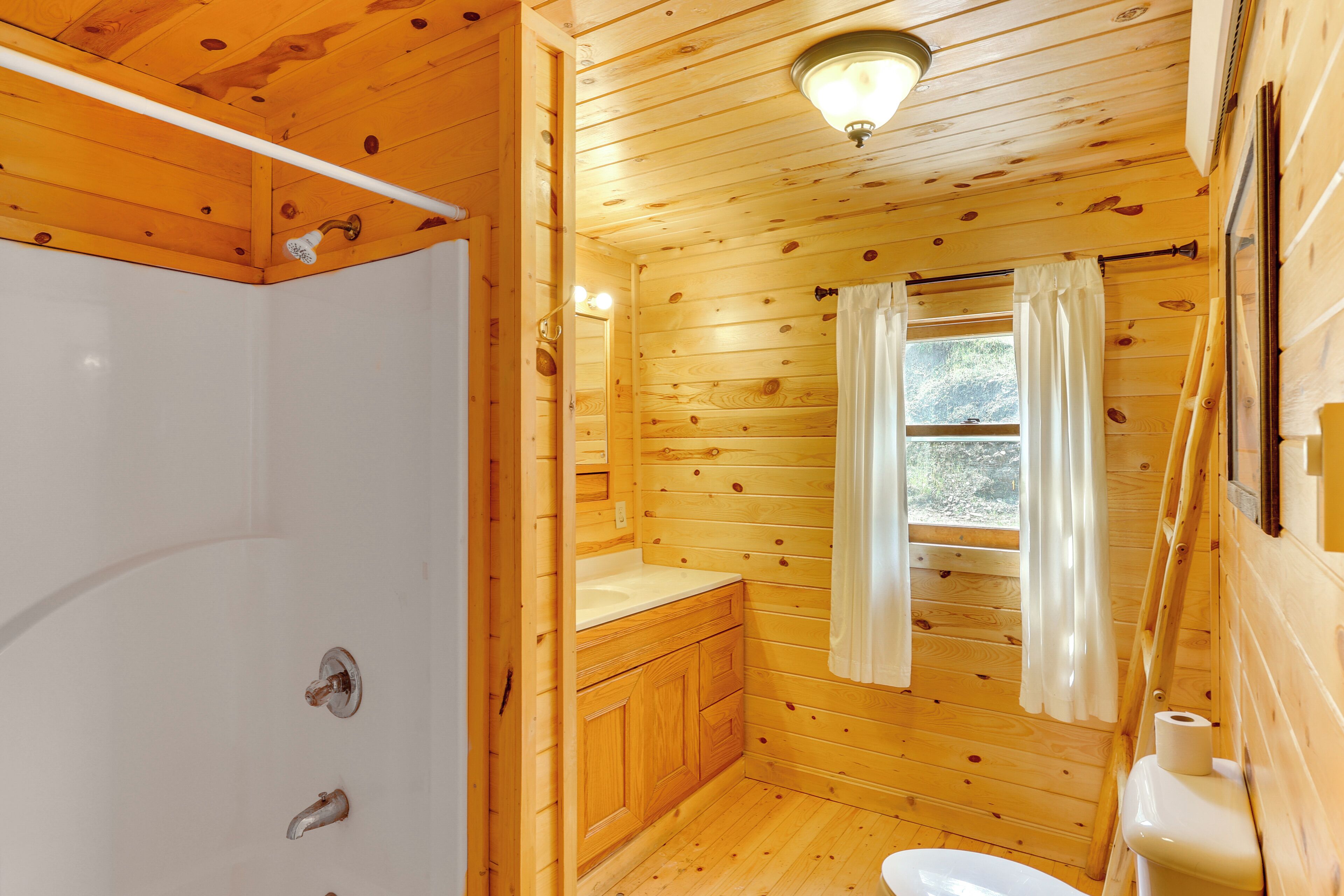 A wooden cabin bathroom with a shower, toilet, and sink.