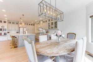 A modern kitchen with white cabinetry, a wooden dining table, and a chandelier. - Luxury Fayetteville Escape w/ Hot Tub & Pool! (Fayetteville)
