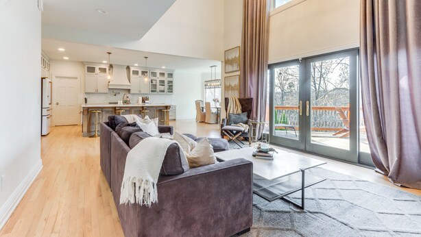 Ein modernes Wohnzimmer mit Sofa, Couchtisch und Blick auf die Küche und den Balkon.
