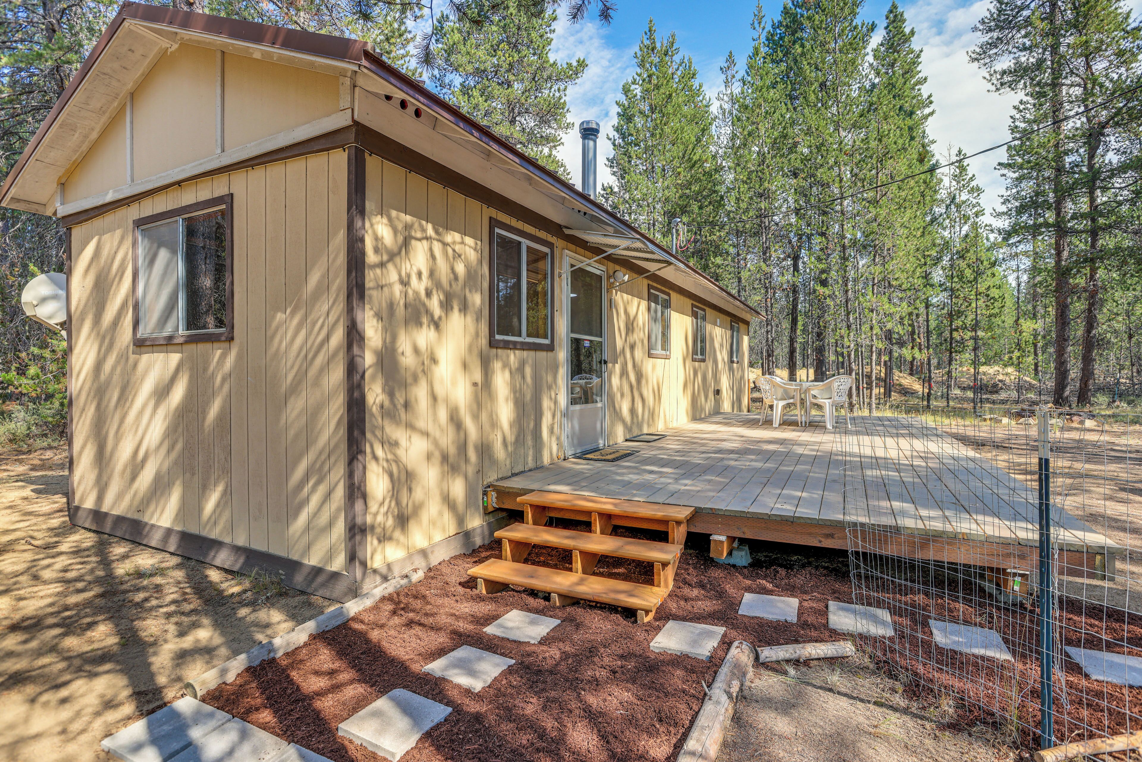 Une cabane en bois dotée d’une terrasse et d’un espace extérieur clôturé.