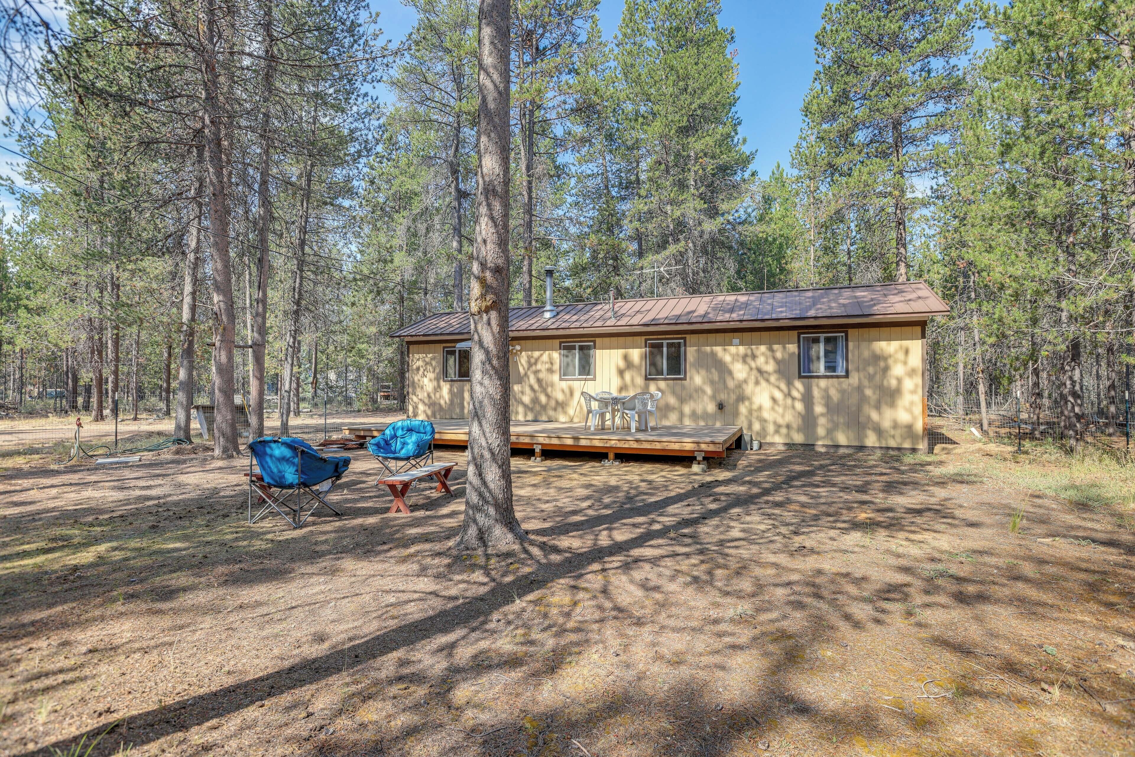 A cabin with a deck, surrounded by tall trees.