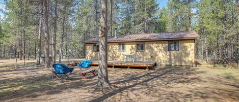 A cabin with a deck, surrounded by tall trees.