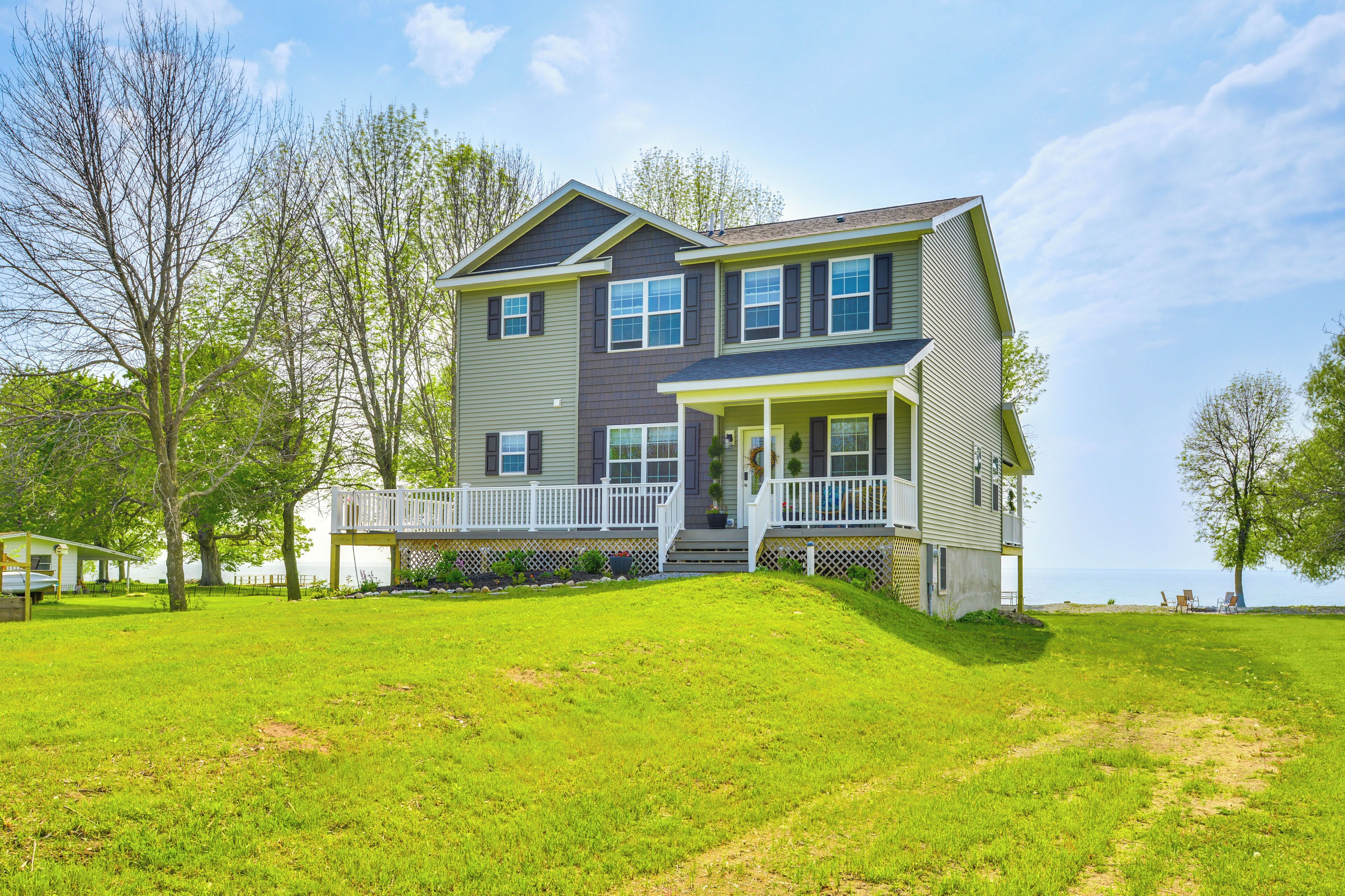 A two-story house with a front porch, a covered deck, and a grassy yard.