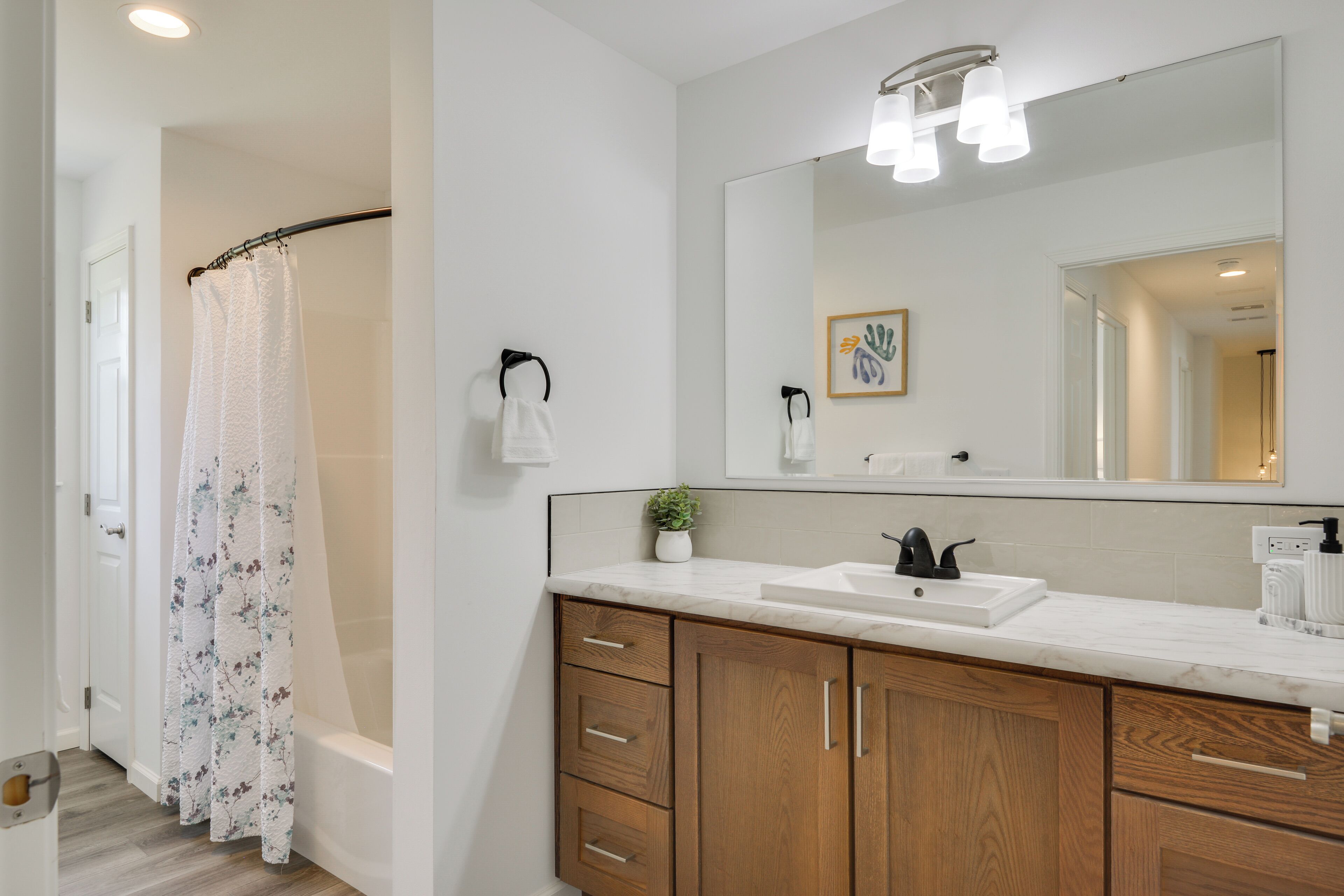 A modern bathroom with a shower, a sink, and a large mirror.