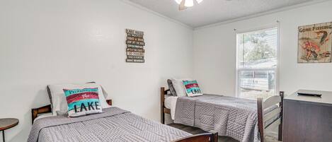 Un dormitorio con dos camas, un ventilador de techo, una ventana y una pared con un cartel que dice 'Gone Fishing'.