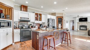 Una cocina moderna con armarios blancos, un refrigerador de acero inoxidable e una isla de madera con taburetes.