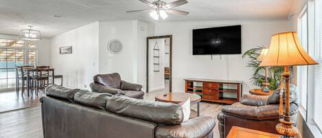 A living room with a brown leather sofa, a wooden coffee table, and a TV mounted on the wall.