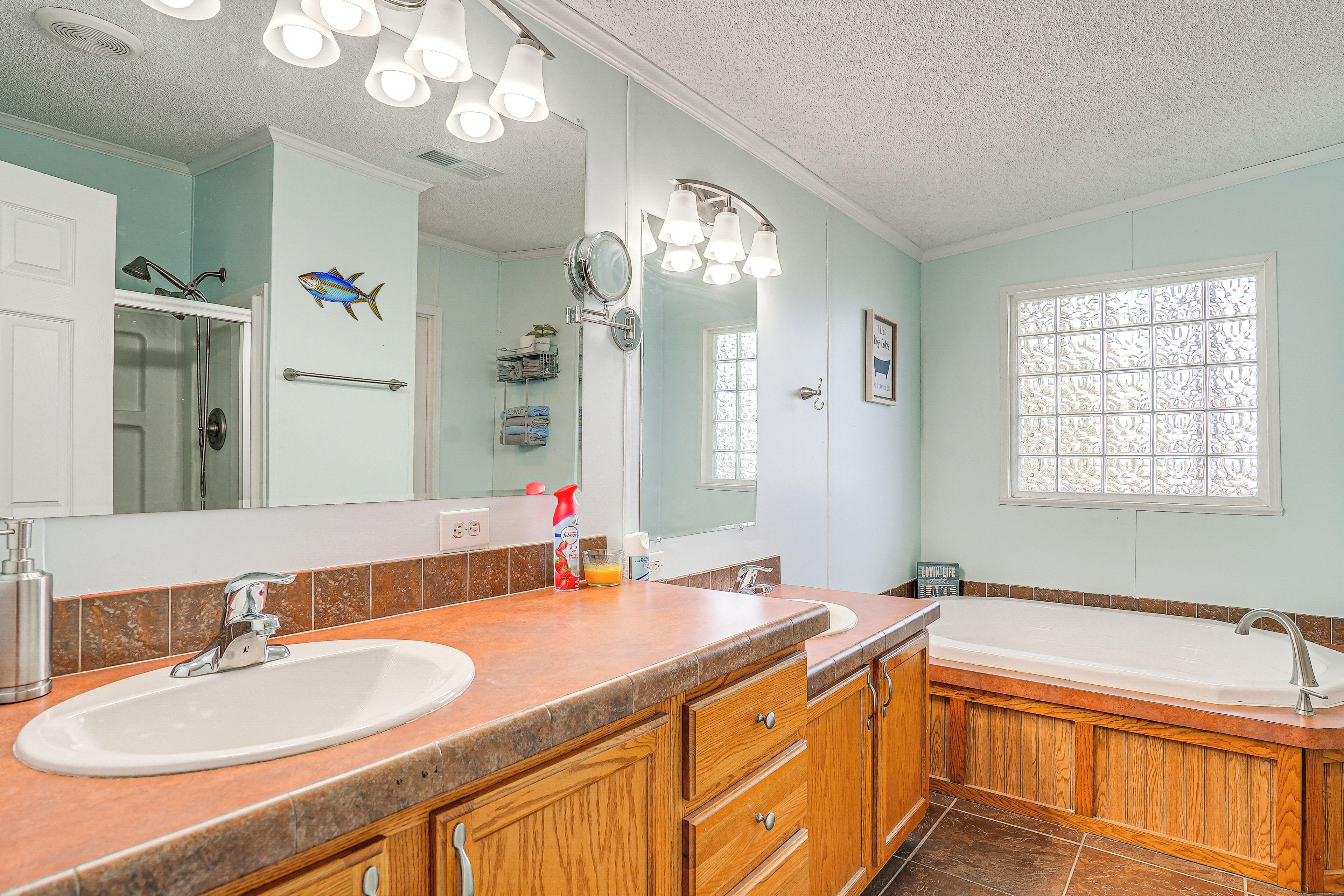 A bathroom with two sinks, a large mirror, and a window with decorative glass.
