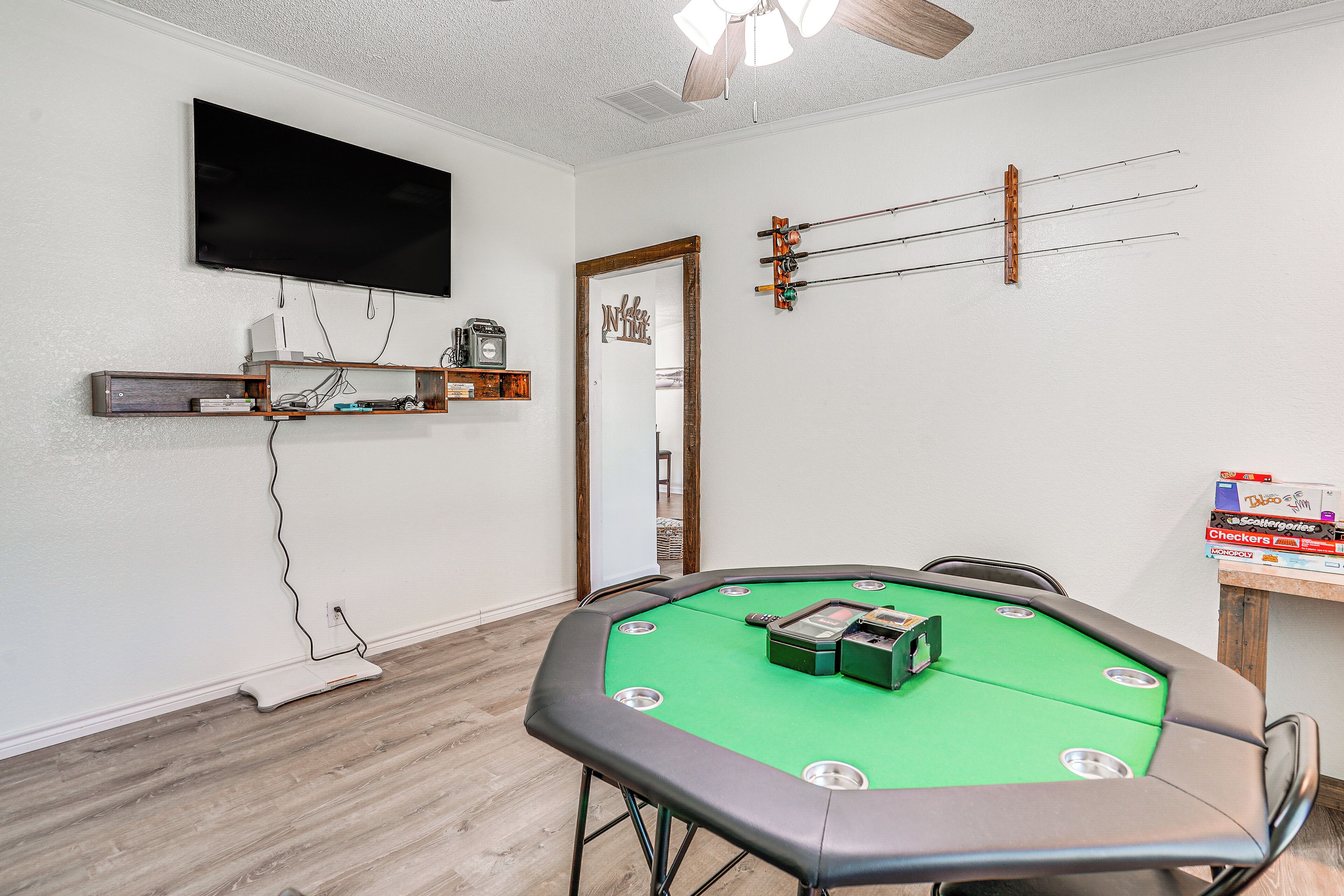 A room with a green pool table, a flat-screen TV mounted on the wall, and a wooden shelf with various items.