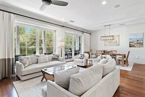 A spacious living room with a sectional sofa, a coffee table, and a dining area with a wooden table and chairs.