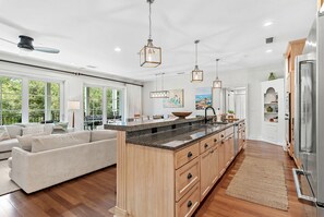 A spacious kitchen with a large island, wooden cabinets, and pendant lighting.