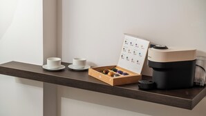 A coffee maker, a box of chocolates, and two cups on a wooden table. - Ypnos Rooms (Naples)