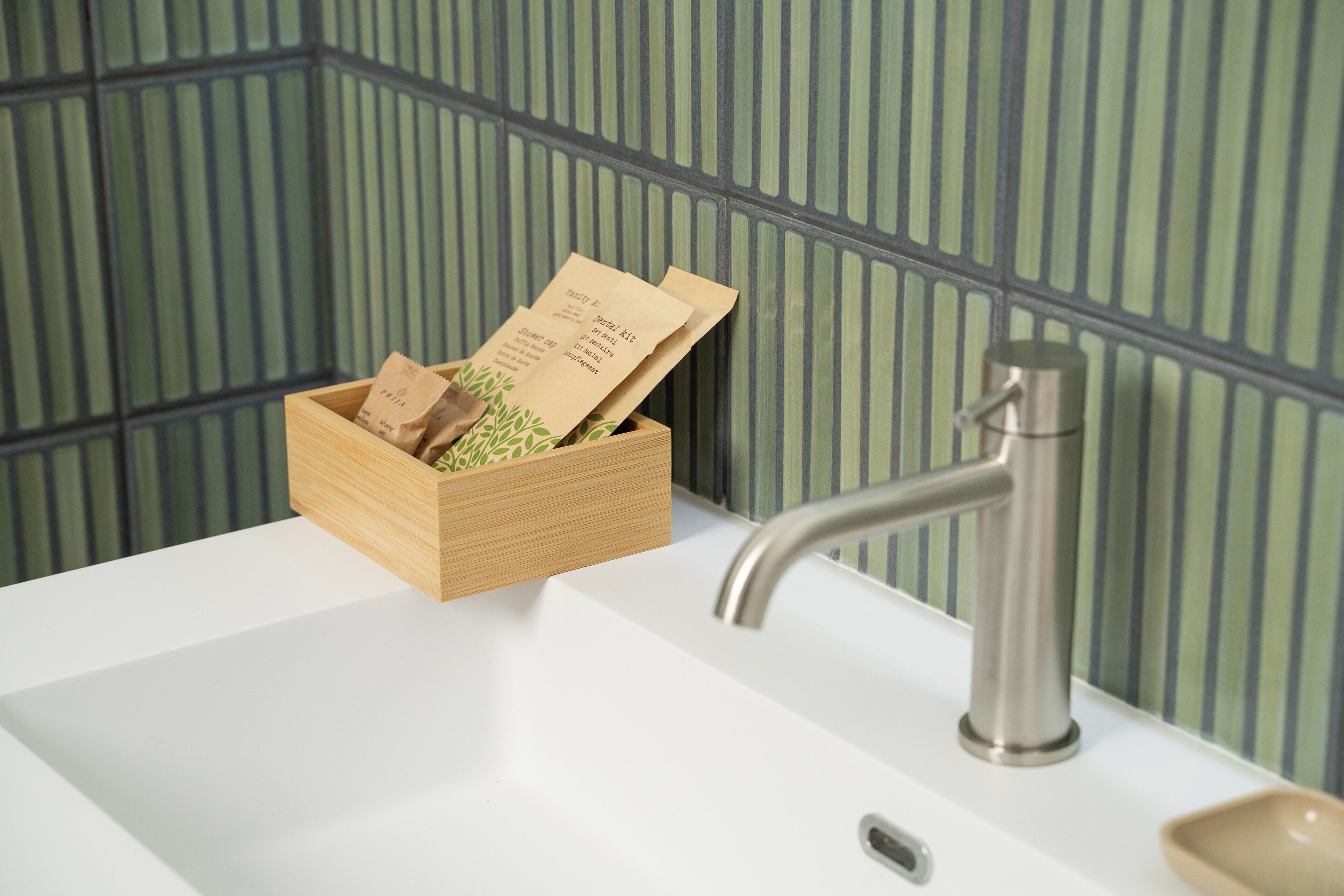 A wooden box with tea bags on a white sink.