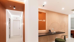 A modern reception area with a reception desk, a neon sign, and a patterned wall. - Ypnos Rooms (Naples)