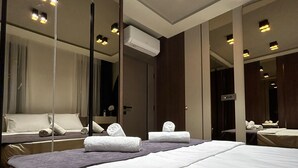 Una habitación de hotel con una cama grande, un espejo y un aire acondicionado instalado en el techo.