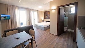 A hotel room with a bed, a desk, a TV, and a bathroom. - Villa Canneto dep.Smeraldo (Sirmione)