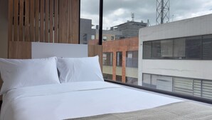 A hotel room with a large bed, wooden panel wall, and a view of the cityscape. - w Marvelous Loft w Modern Deco in Bogota (Bogotá)