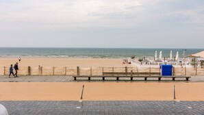 A beach promenade with a wooden walkway, benches, and umbrellas. - Stunning Seafront Apartment With Modern Comforts and Dike Views (Ostend)