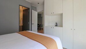 A modern hotel room with a large bed, a wardrobe, and a visible dining area in the background. - w Resplendent 2BR w Great Balcony in San Isidro (Lima)