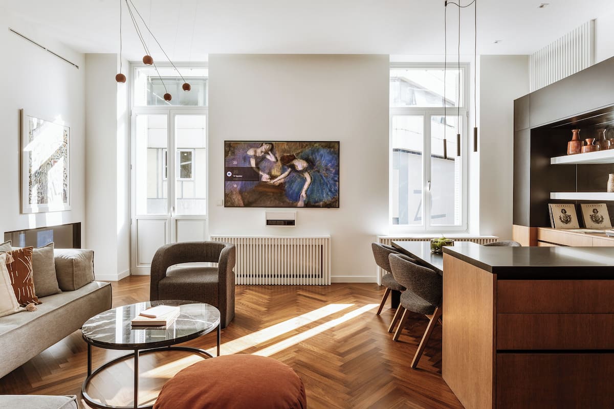 A modern living room with a large painting, a sofa, a coffee table, and a dining area.