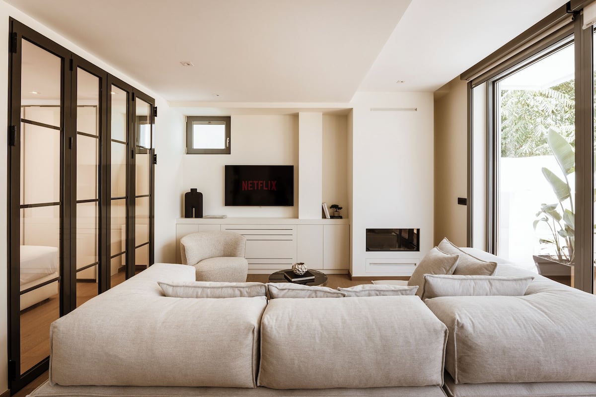 A modern living room with a sectional sofa, a flat-screen TV, and a fireplace.