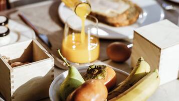 A breakfast setting with a wooden crate, a plate with a pear, an onion, and bananas, and a glass of orange juice.