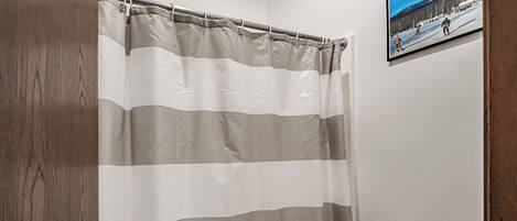 A bathroom with a striped shower curtain, a toilet, and a framed picture on the wall.