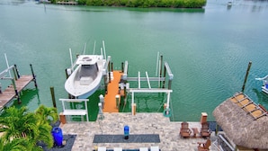 A boat docked at a pier with a pool area and lounge chairs. - Charming 4-bedroom house in fabulous Key Colony Beach with AC, WIFI, Boatlift,  (Key Colony Beach)