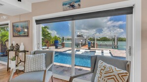 A poolside area with a view of a marina, a glass door, and striped chairs. - Charming 4-bedroom house in fabulous Key Colony Beach with AC, WIFI, Boatlift,  (Key Colony Beach)