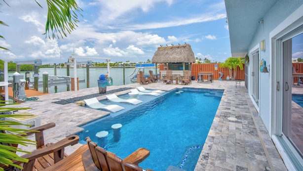 A swimming pool with lounge chairs and a thatched-roof structure. - Charming 4-bedroom house in fabulous Key Colony Beach with AC, WIFI, Boatlift,  (Key Colony Beach)