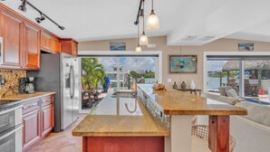 A spacious kitchen with a large island, stainless steel appliances, and a view of a pool and outdoor seating area. - Charming 4-bedroom house in fabulous Key Colony Beach with AC, WIFI, Boatlift,  (Key Colony Beach)