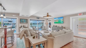 A spacious living area with a large window, a ceiling fan, a pool view, and a door marked "EXIT". - Charming 4-bedroom house in fabulous Key Colony Beach with AC, WIFI, Boatlift,  (Key Colony Beach)