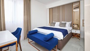 A hotel room with a bed, a desk, a chair, a bedside table, and a mirror. - Moderna Luxury Apartments-One bedroom with terrace 2

 (Tivat)