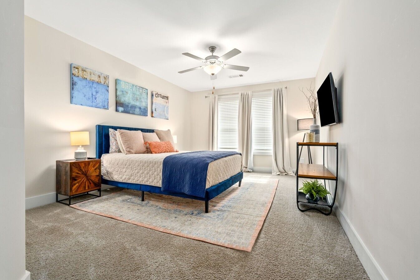 A bedroom with a bed, a nightstand, a TV, and artwork on the wall.