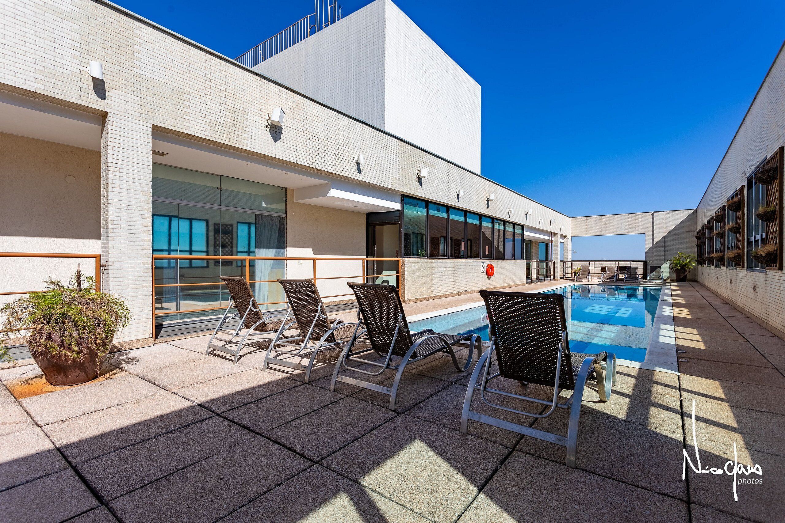 A rooftop pool area with lounge chairs and a potted plant.
