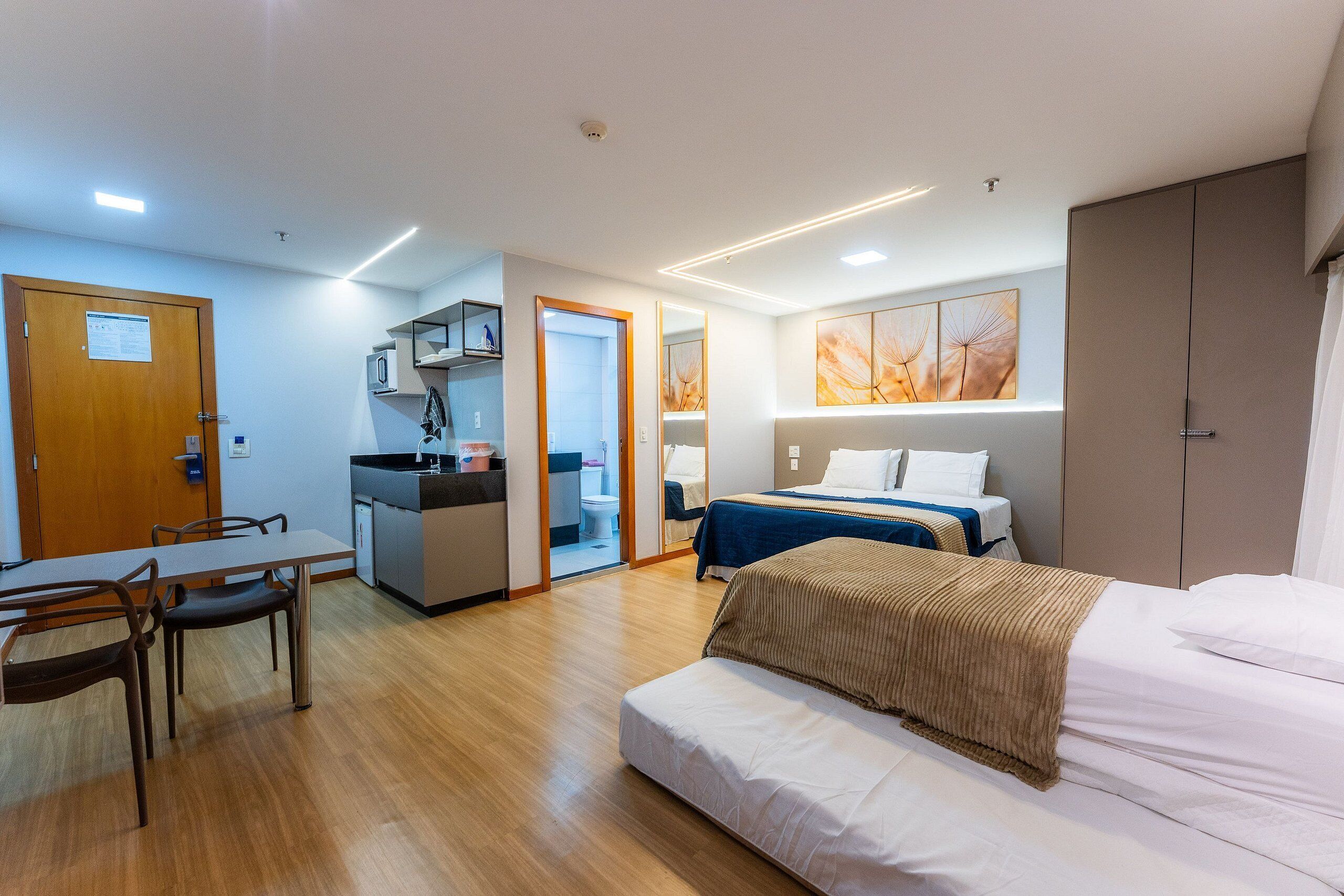 Una habitación de hotel pequeña con cama, escritorio y kitchenette.