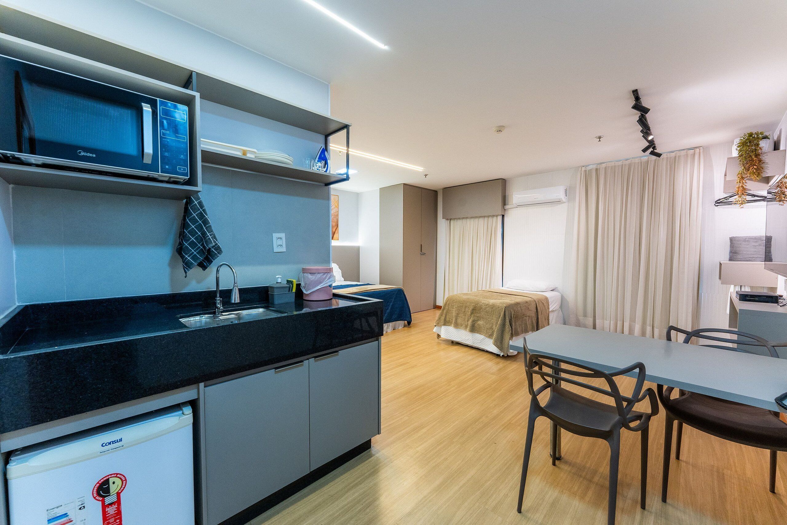 A modern kitchen with a microwave, refrigerator, and sink. There is a dining area with a table and chairs.