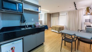 Une cuisine moderne équipée d’un four à micro-ondes, d’un réfrigérateur et d’un évier. Un coin repas avec une table et des chaises est également disponible.