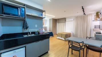 A modern kitchen with a microwave, refrigerator, and sink. There is a dining area with a table and chairs.