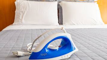 Um ferro da Elgin sobre uma cama com manta acolchoada e almofadas brancas.