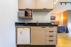 Una cucina compatta con frigorifero, forno a microonde e lavandino.
