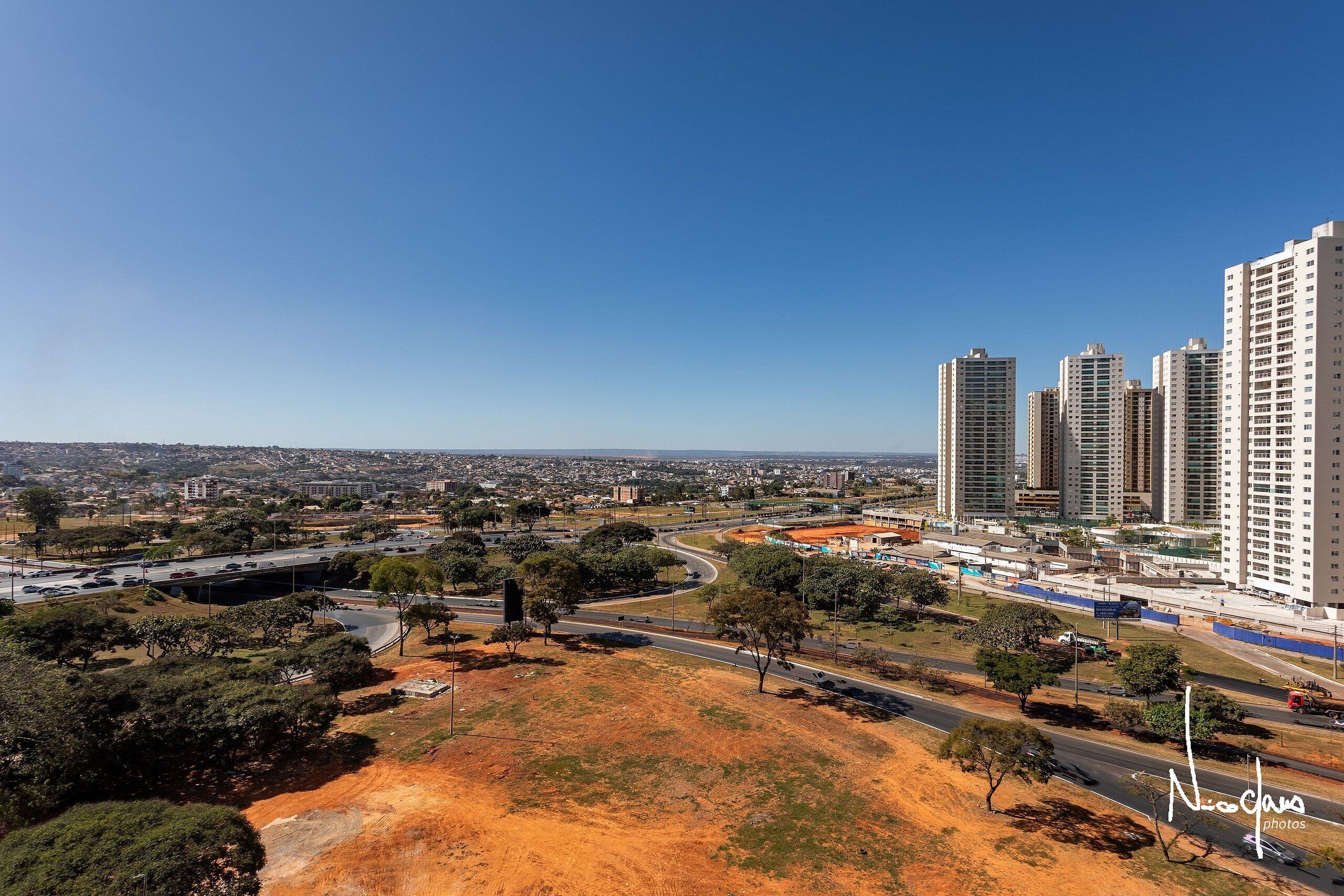 A high-rise building complex with multiple floors, surrounded by a mix of greenery and urban infrastructure.