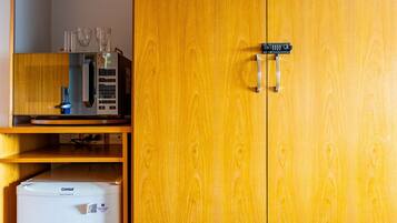 A wooden wardrobe with a microwave and a small refrigerator inside.
