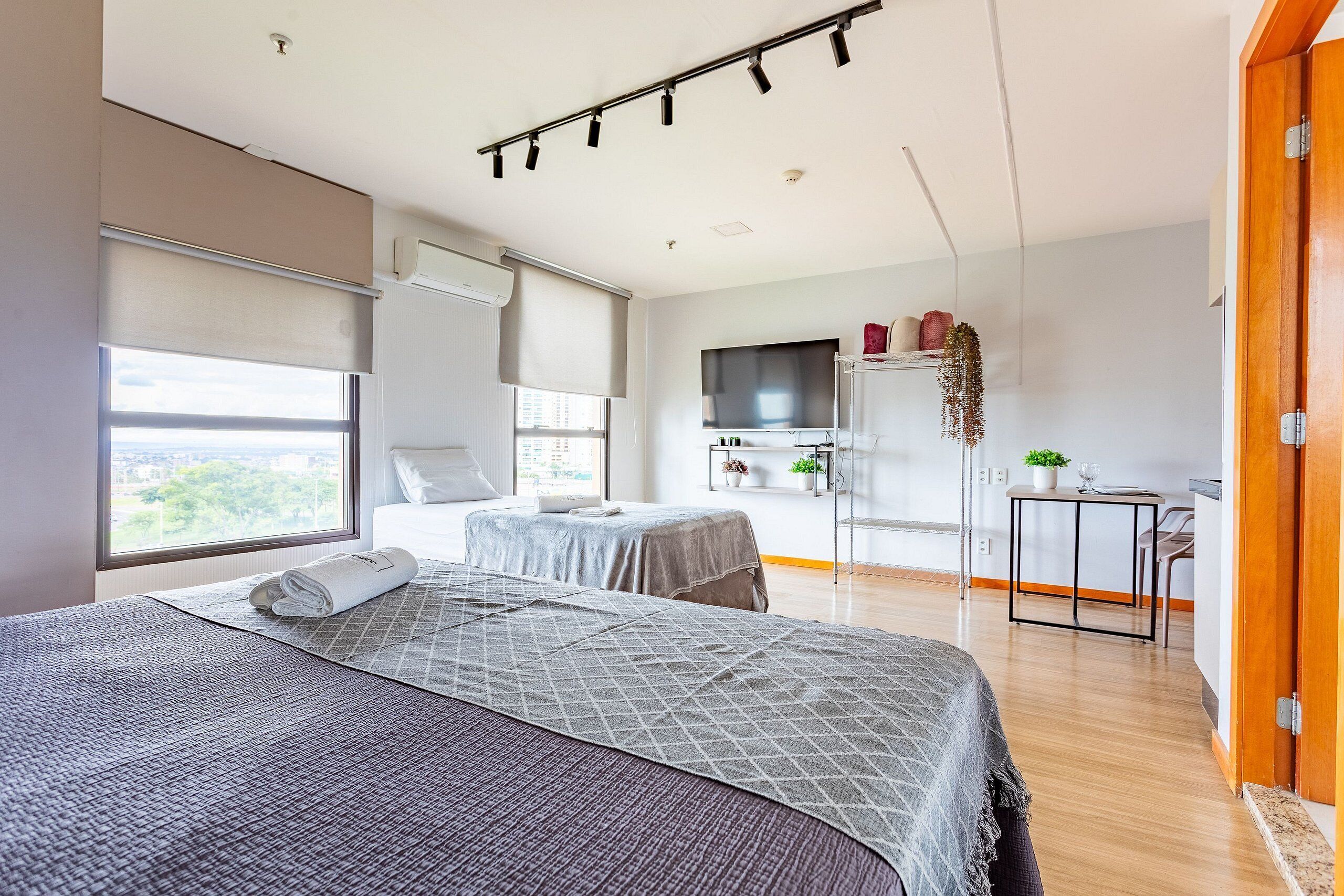 A modern bedroom with a large bed, a desk, and a TV.