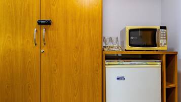 Un armario de madera con dos puertas, un refrigerador blanco pequeño y un microondas encima de un estante de madera.