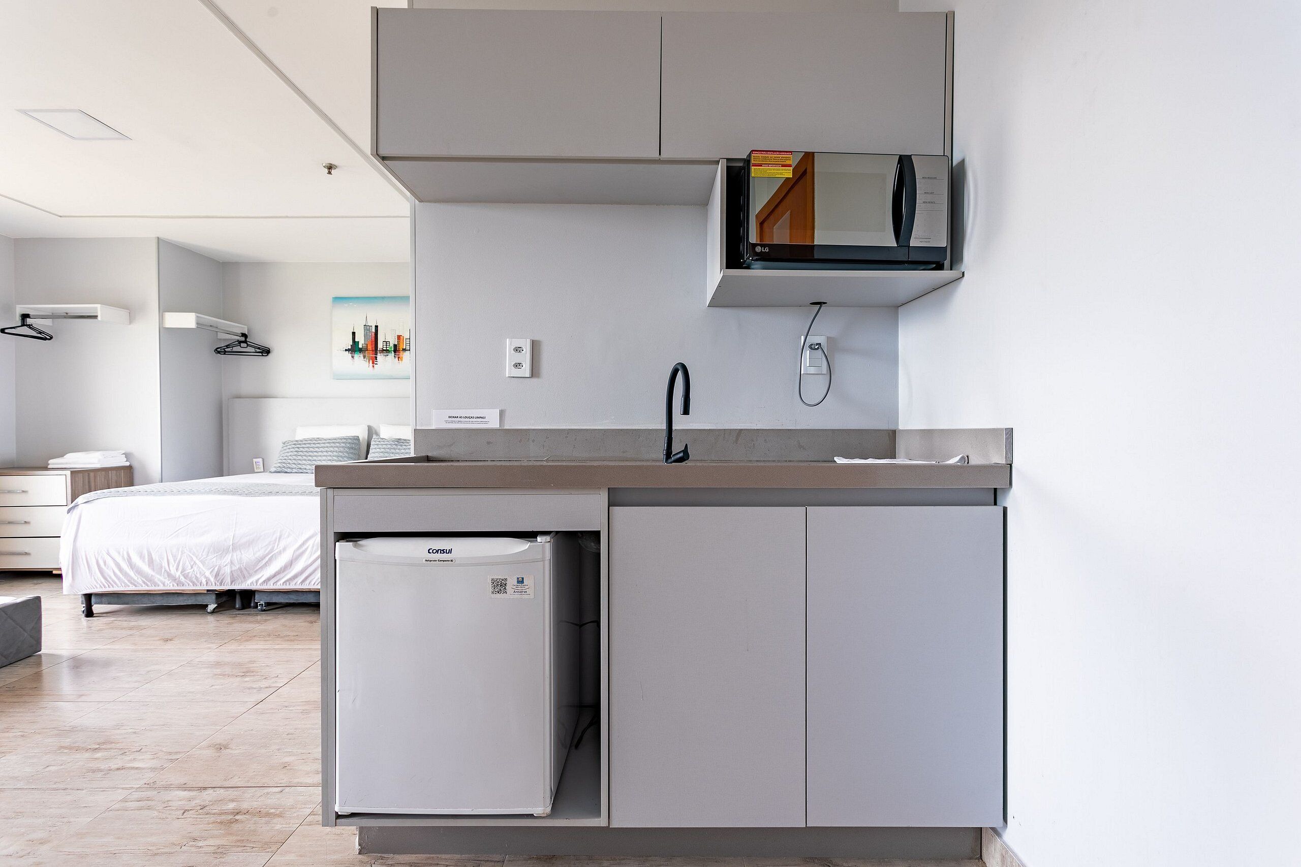 Una cocina moderna con microondas integrado, refrigerador y pileta.
